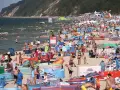 Tłum ludzi na plaży, w wodzie i na piasku. Wiele kolorowych parawanów i parasoli. W tle klif porośnięty lasem. Czy Morze Czarne jest ciepłe? Tłumy sugerują, że tak!