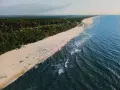 Widok z lotu ptaka na piaszczystą plażę, las i morze w Jastrzębiej Górze.