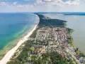 Widok z lotu ptaka na Mielno: plaża, morze, jezioro i zabudowania.
