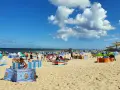 Władysławowo z dzieckiem: plaża pełna kolorowych parawanów, ludzi odpoczywających i bawiących się na piasku, w tle morze i zjeżdżalnie wodne.