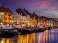 Magiczny wieczór w Kopenhadze, idealny na wycieczkę Świnoujście-Kopenhaga-Malmö. Kanał rozświetlony lampkami, kolorowe kamienice i łodzie tworzą bajkową atmosferę.