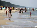 Ludzie kąpią się w Bałtyku, szukając miejsca, gdzie jest najcieplejsza woda. Słoneczny dzień na plaży z rodzinami i dziećmi.