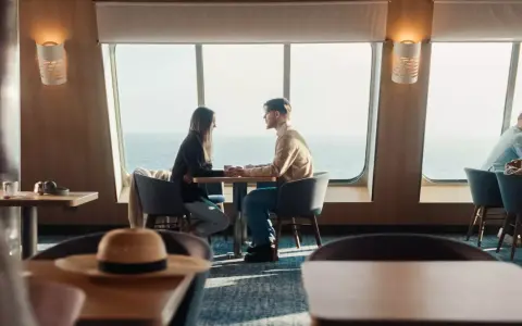 Para zakochanych trzyma się za ręce przy oknie na statku Stena Line. Romantyczne chwile i atrakcje na morzu.