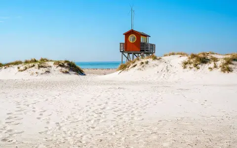 Piękne plaże w Szwecji z charakterystyczną czerwoną wieżą ratowniczą na wydmach.