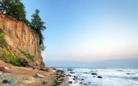 Piękna linia brzegowa Bałtyku w Polsce z klifem porośniętym drzewami i piaszczystą plażą.