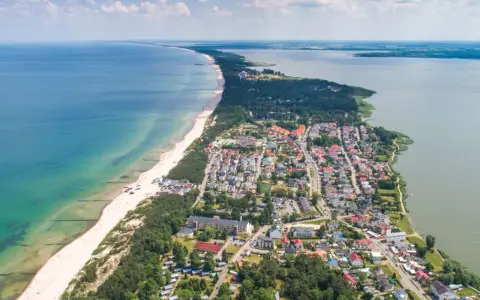 Widok z lotu ptaka na Mielno: plaża, morze, jezioro i zabudowania.