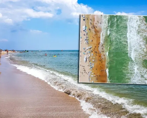 Plaża pełna ludzi, fale rozbijają się o brzeg. Czy Morze Czarne jest czyste? Woda wygląda na zieloną i przejrzystą.