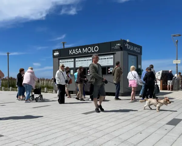 Ludzie stojący w kolejce do kasy biletowej "Kasa Molo" w Kołobrzegu.