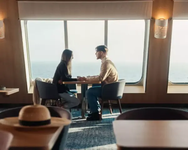 Para zakochanych trzyma się za ręce przy oknie na statku Stena Line. Romantyczne chwile i atrakcje na morzu.