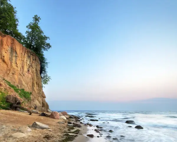Piękna linia brzegowa Bałtyku w Polsce z klifem porośniętym drzewami i piaszczystą plażą.