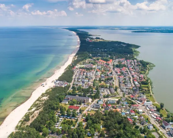 Widok z lotu ptaka na Mielno: plaża, morze, jezioro i zabudowania.