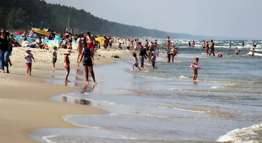 Ludzie kąpią się w Bałtyku, szukając miejsca, gdzie jest najcieplejsza woda. Słoneczny dzień na plaży z rodzinami i dziećmi.