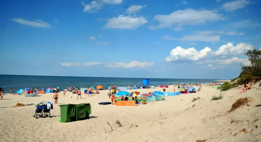 Plaża pełna ludzi, kolorowe parawany i namioty. Idealne miejsce, gdzie ciepła woda w czerwcu zachęca do kąpieli.