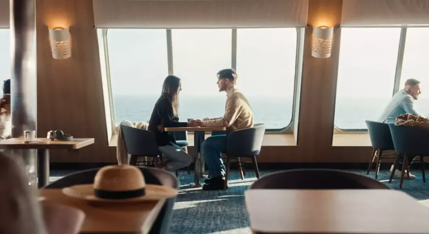 Para zakochanych trzyma się za ręce przy oknie na statku Stena Line. Romantyczne chwile i atrakcje na morzu.