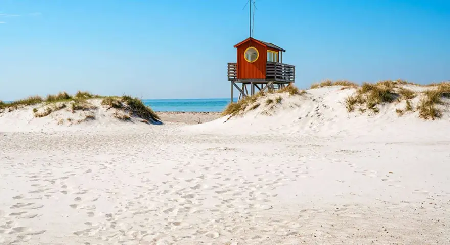 Piękne plaże w Szwecji z charakterystyczną czerwoną wieżą ratowniczą na wydmach.