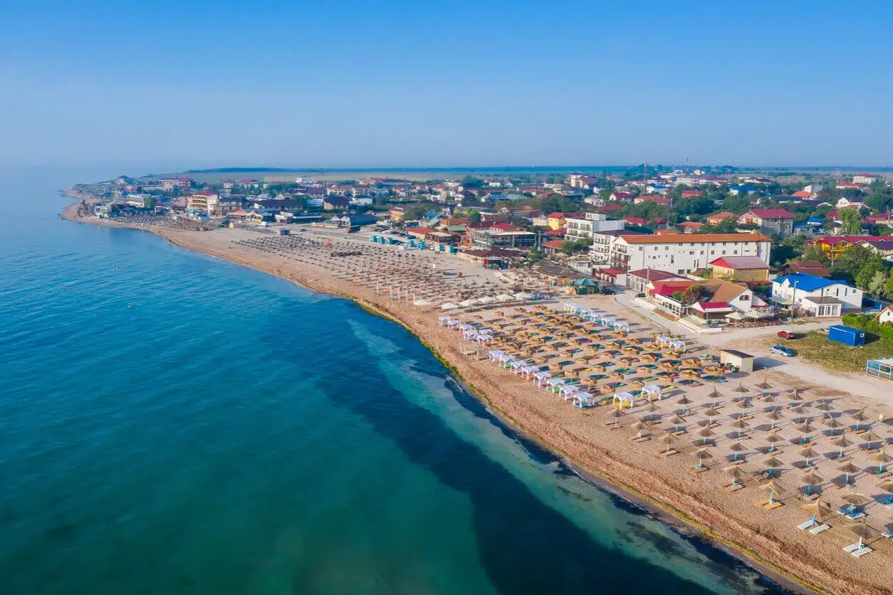 Plaża nad Morzem Czarnym, pełna leżaków i parasoli. Woda wygląda na ciepłą, idealną do kąpieli.