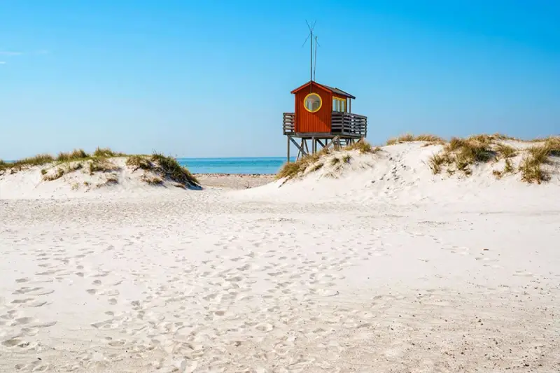 Piękne plaże w Szwecji z charakterystyczną czerwoną wieżą ratowniczą na wydmach.